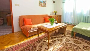 A living room with a sofa, a table, a rug, a painting, and a window with curtains. - Holiday apartment with air conditioning (Valbandon)
