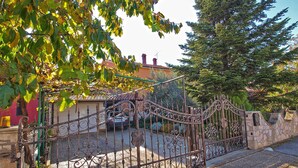 A wrought iron gate with a stone wall and a parked car in the background. - Holiday apartment with air conditioning (Valbandon)
