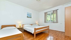 Ein Zimmer mit zwei hölzernen Betten, einem Vorhangfenster, einem Gemälde an der Wand und einem Kleiderschrank.