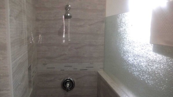 A bathroom with a shower, tiled walls, and a bathtub.