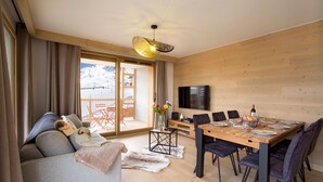 Un salon moderne avec un canapé, une table à manger dressée pour six personnes et un téléviseur fixé au mur.