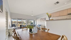 Une salle à manger moderne avec une table en bois, des chaises et un vase rempli de fleurs.