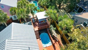 A rooftop pool area with a hot tub, surrounded by palm trees and a wooden deck. - Swim Spa, Tiki Bar, Pet friendly, Fenced yard, 3 min walk to beach - The Blue House (Isle Of Palms)
