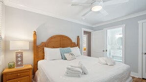 A neatly made bed with white linens and towels, a wooden headboard, and a bedside table with a lamp and decorative items. - Oasis w/ Private Pool, Pets considered, 2 Houses from beach access- The Pink House (Isle Of Palms)