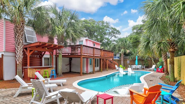 A backyard with a swimming pool, lounge chairs, and a wooden deck. - Oasis w/ Private Pool, Pets considered, 2 Houses from beach access- The Pink House (Isle Of Palms)