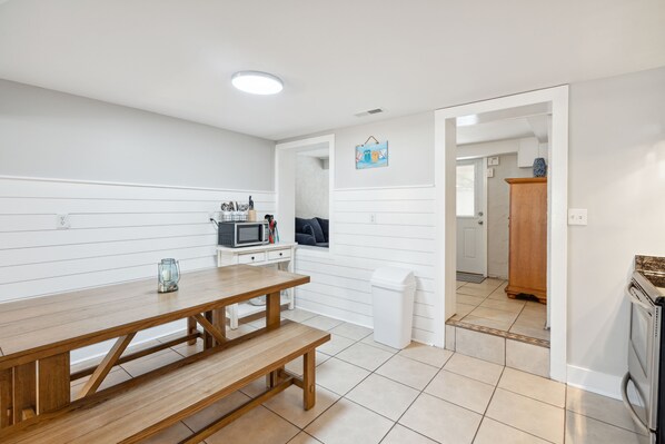 Una cocina moderna con una mesa de madera, armarios blancos y un microondas.