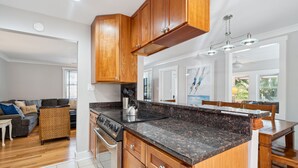 A modern kitchen with wooden cabinets, a granite countertop, and stainless steel appliances. - Oasis w/ Private Pool, Pets considered, 2 Houses from beach access- The Pink House (Isle Of Palms)