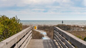 A wooden boardwalk leading to a beach with a sandy path and a yellow trash bin. - 501 MOORINGS - Marina View, Pool. Fully renovated. Perfect for Family, Boaters, Golfers (Isle Of Palms)