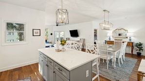 A spacious kitchen with a central island, white cabinetry, and a large window. - 501 MOORINGS - Marina View, Pool. Fully renovated. Perfect for Family, Boaters, Golfers (Isle Of Palms)