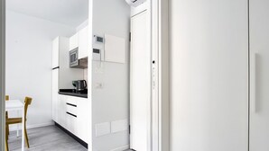 Une cuisine moderne avec des meubles blancs, un four à micro-ondes et une bouilloire.