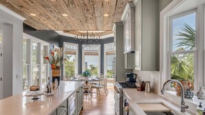 A spacious kitchen with a central island, large windows, and a wooden ceiling. - 7 Bedroom Oceanview Kiawah Vanderhorst Estate with Pool (Kiawah Island)