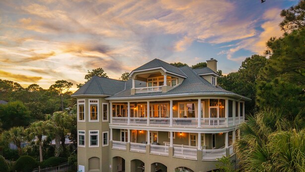 A large two-story house with a balcony, a swimming pool, and lush greenery. - 7 Bedroom Oceanview Kiawah Vanderhorst Estate with Pool (Kiawah Island)