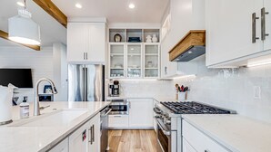 Une cuisine moderne avec des meubles blancs, des appareils électroménagers en acier inoxydable et un plancher en bois.