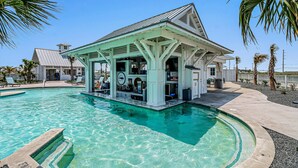 Un espace piscine doté d’un bar couvert et de chaises longues.
