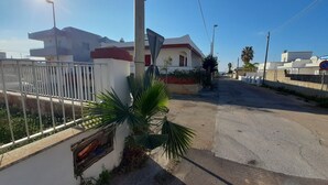 Una calle residencial con casas, una valla blanca y una palmera.