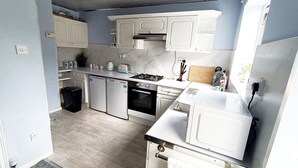 A compact kitchen with white cabinets, a built-in oven, a microwave, and a sink.