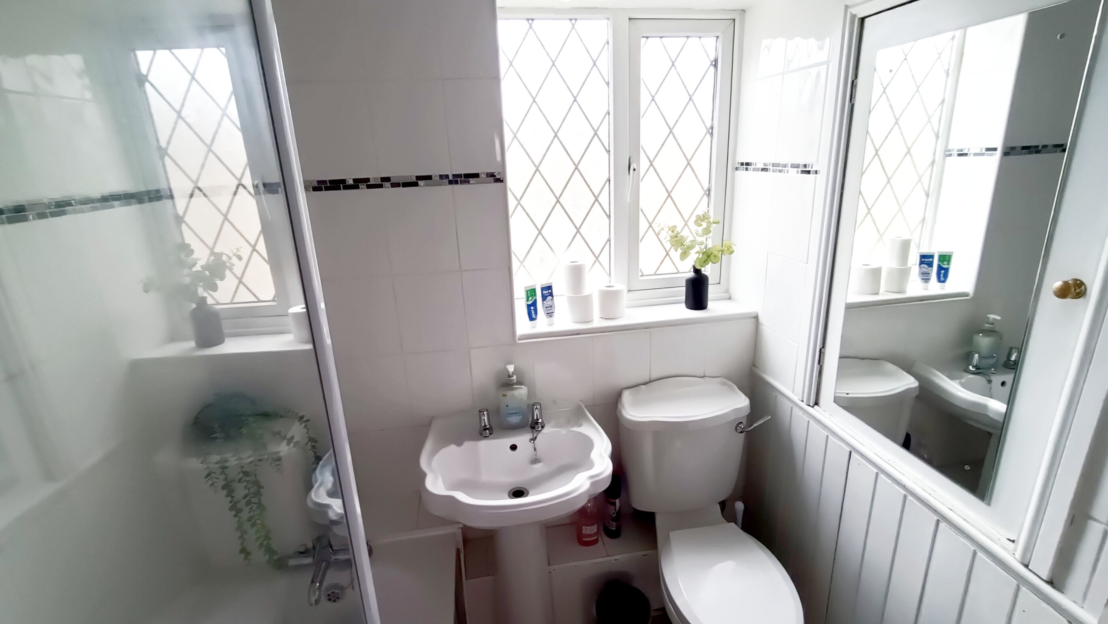 A bathroom with a toilet, sink, and window with a view.