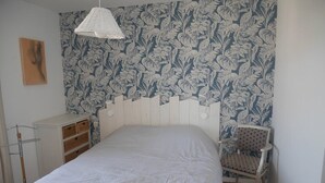 Un dormitorio con cama, una silla, un armario y un papel pintado con motivos.