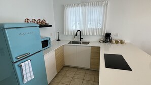 A compact kitchen with a blue refrigerator, a sink, a coffee maker, and a small countertop. - Hojo House Winnipeg (Winnipeg)