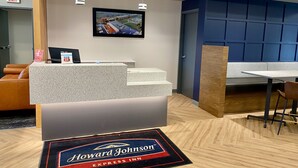 A hotel reception area with a reception desk, a television mounted on the wall, and a seating area with a table and chairs. - Hojo House Winnipeg (Winnipeg)