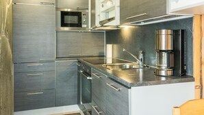 Una cocina moderna con electrodomésticos de acero inoxidable, horno empotrado, cafetera y lavamanos.