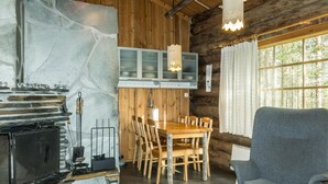 Interior rústico de una cabaña con chimenea de piedra, una mesa de comedor de madera y sillas.