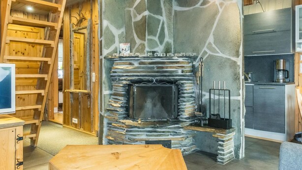Una sala de estar acogedora con chimenea de piedra, muebles de madera y una cocina equipada con electrodomésticos modernos.
