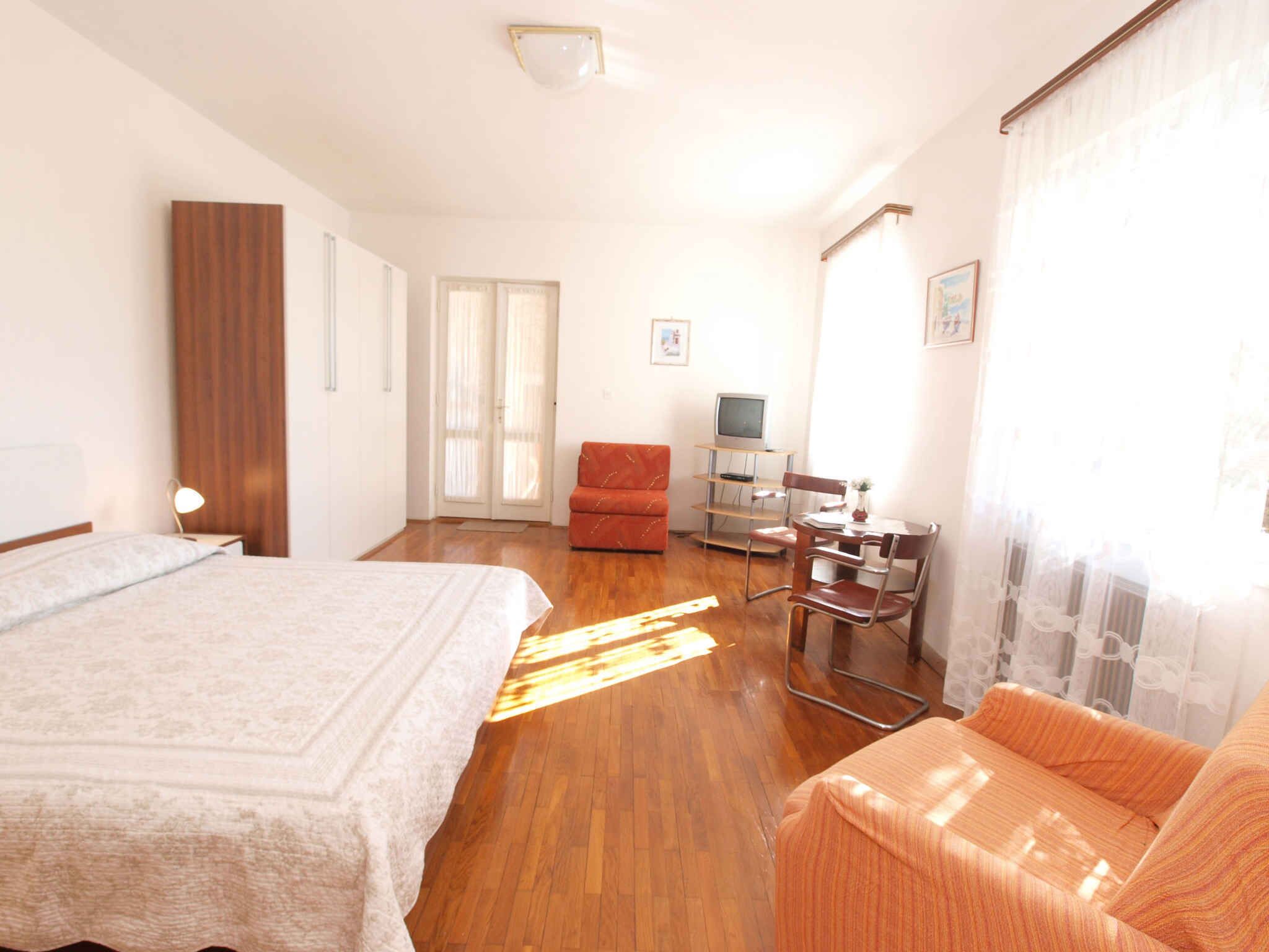 Ein Schlafzimmer mit einem Bett, einem Schreibtisch mit Computer, einem Stuhl und einer Couch.