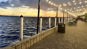 A waterfront promenade with string lights, a brick walkway, and a railing overlooking the sea. - Punta Gorda Canal Waterfront I Pool, Kayaks, Bikes, Boat Dock (Punta Gorda)