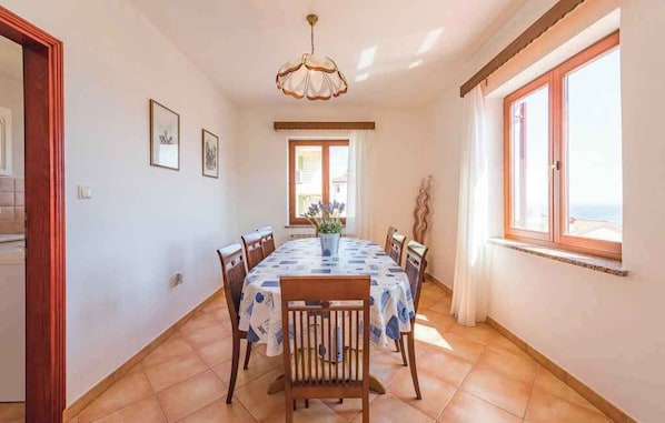A dining area with a round table, chairs, and a chandelier.