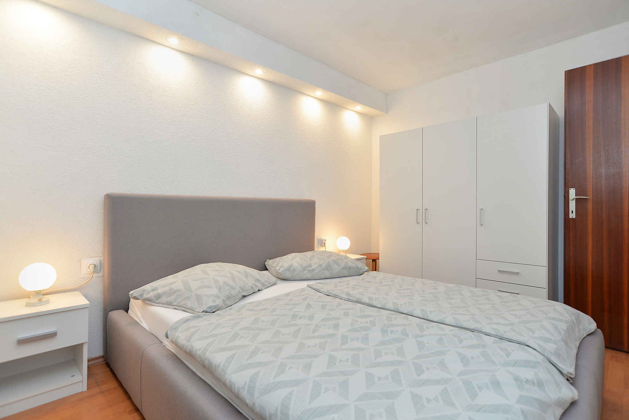 Une chambre à coucher avec un lit, des tables de chevet et une armoire.