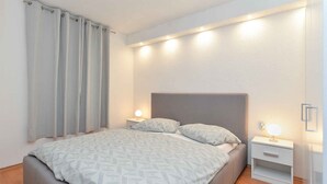Een slaapkamer met een bed, twee nachtkastjes en een bijzetmeubel met een lamp.