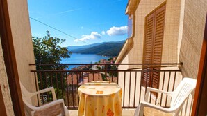 Un balcon avec une table et deux chaises, offrant une vue panoramique sur un lac et des montagnes.