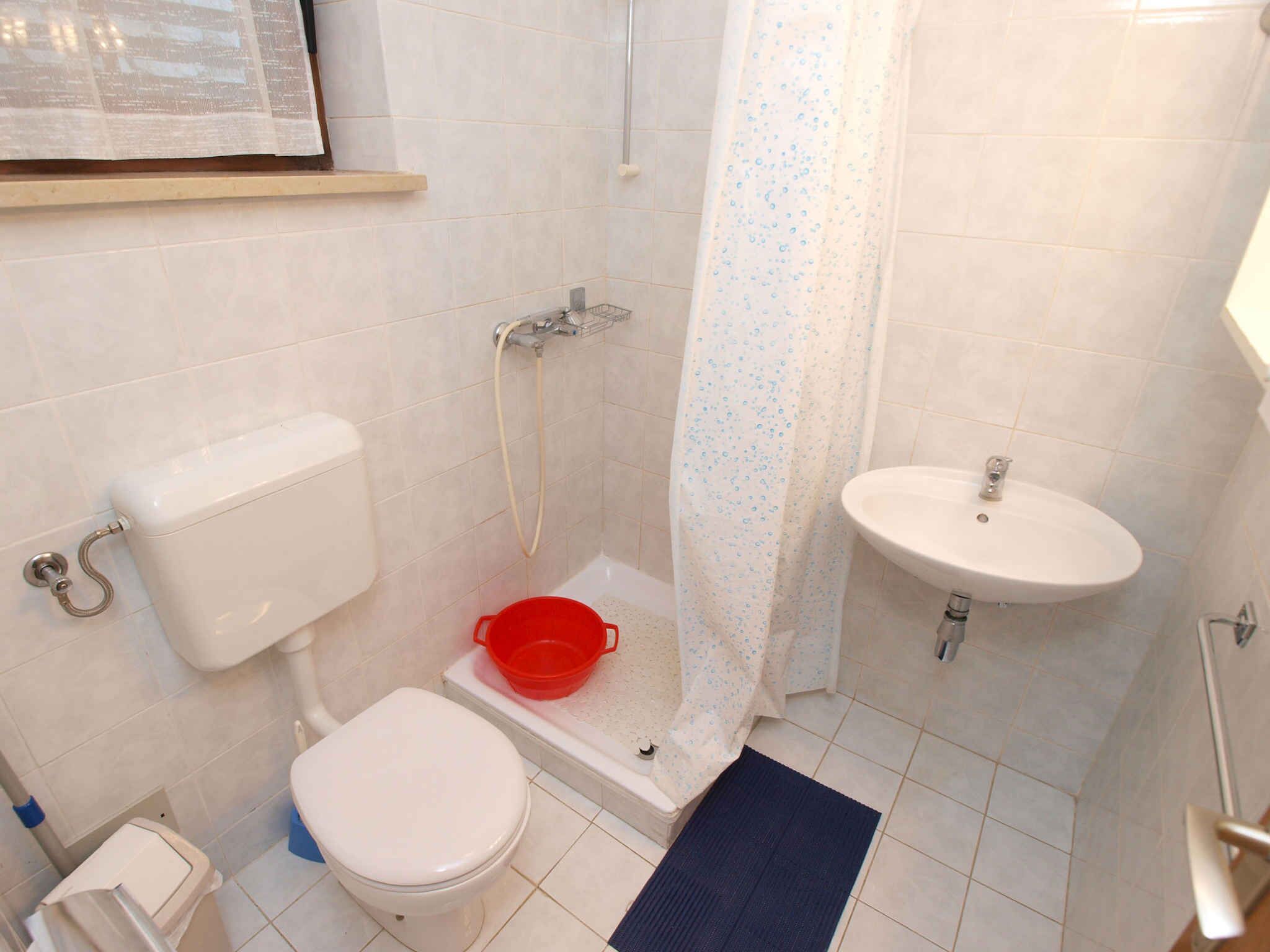 A small bathroom with a toilet, a shower, and a sink.