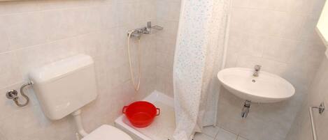 A small bathroom with a toilet, a shower, and a sink.