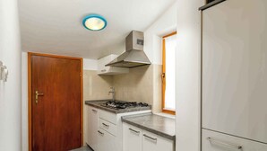A compact kitchen with a stove, cabinets, and a wooden door.