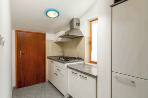 A compact kitchen with a stove, cabinets, and a wooden door.