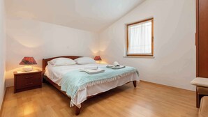 A bedroom with a bed, nightstands, a window, and a wooden floor.