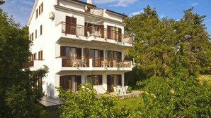 A two-story building with balconies and a garden. - Holiday apartment with air conditioning (Rabac)