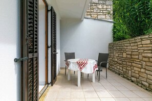 Eine Terrasse mit Tisch und Stühlen, eine Steinmauer und eine Tür mit einem Metallgitter.