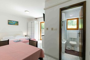 Ein Hotelzimmer mit Bett, Tisch, Bad mit Toilette und Waschbecken sowie einem Fenster.