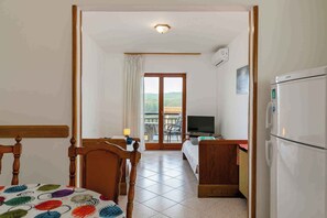 Ein Hotelzimmer mit Bett, Schreibtisch, Fernseher, Kühlschrank und Blick ins Freie.