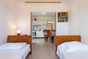 A hotel room with two beds, a small kitchen, and a dining area. - Holiday apartment with air conditioning (Rabac)