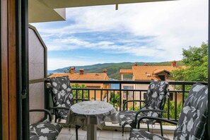 Ein Balkon mit Tisch und Stühlen, der Blick auf terrassenförmig angeordnete Häuser und Hügeln bietet.