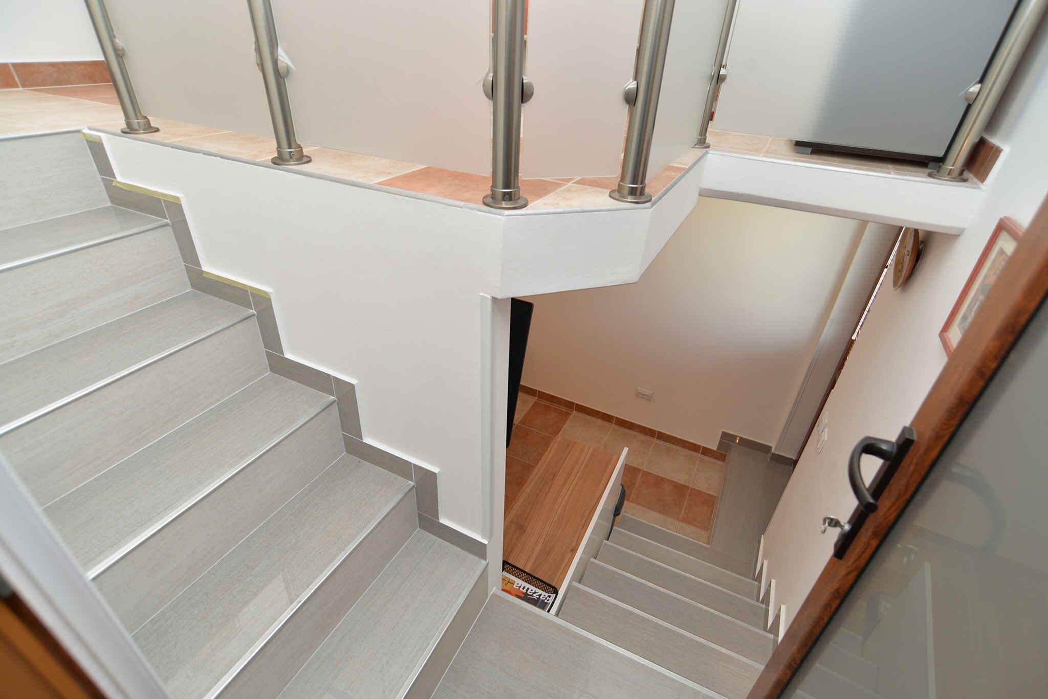 A staircase with a handrail, leading to a landing with a door and a small shelf.