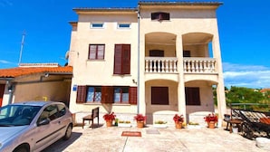 A two-story building with a balcony and a car parked in front. - Holiday apartment with balcony (Valbandon)