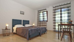 A bedroom with a bed, bedside lamps, a chair, and a window with blinds. - Holiday apartment with balcony (Valbandon)