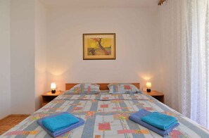 Habitació d'hotel amb llit, dues taules de nit amb làmpades, un quadre a la paret i una finestra amb cortines.