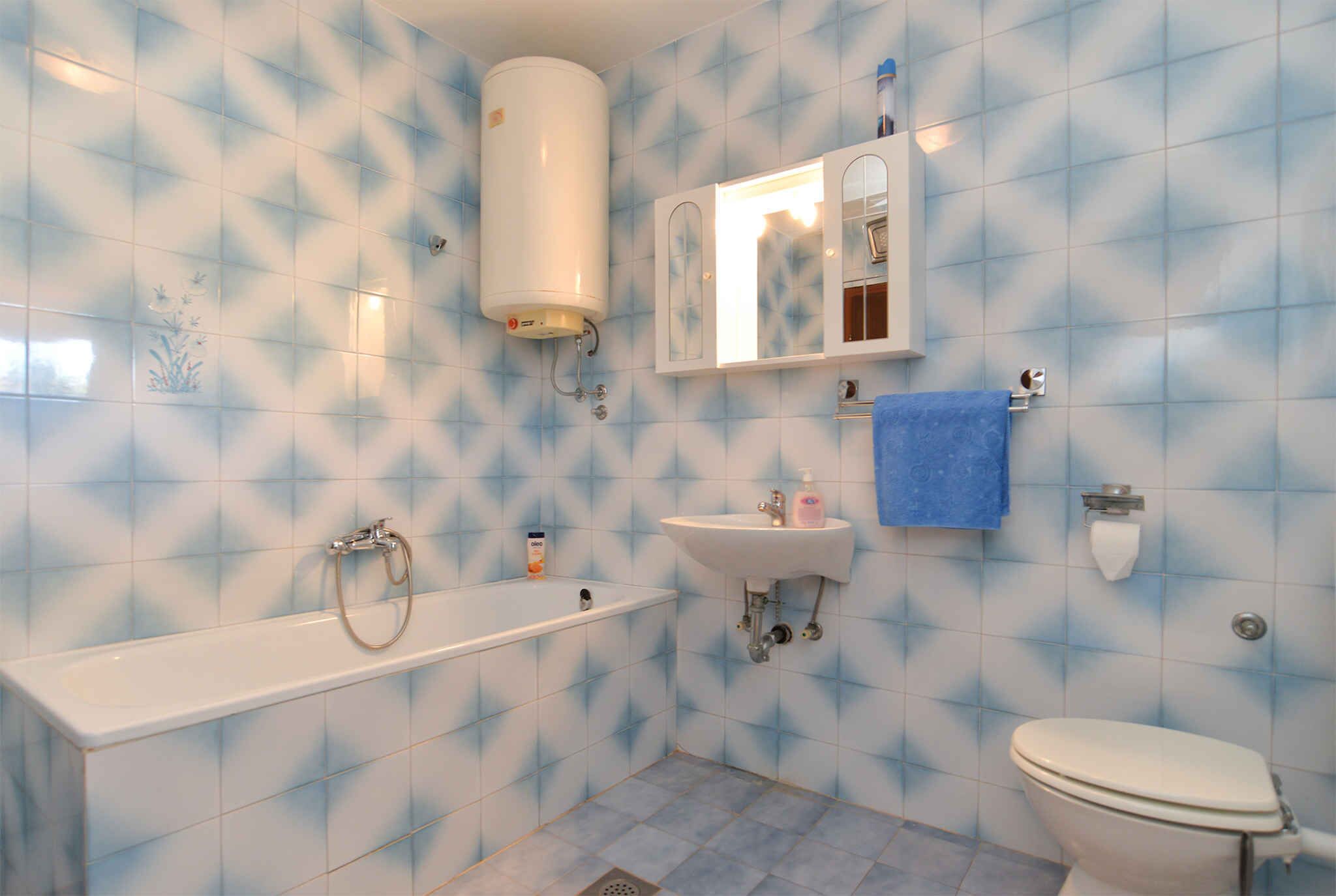 A bathroom with a bathtub, sink, toilet, and a water heater.
