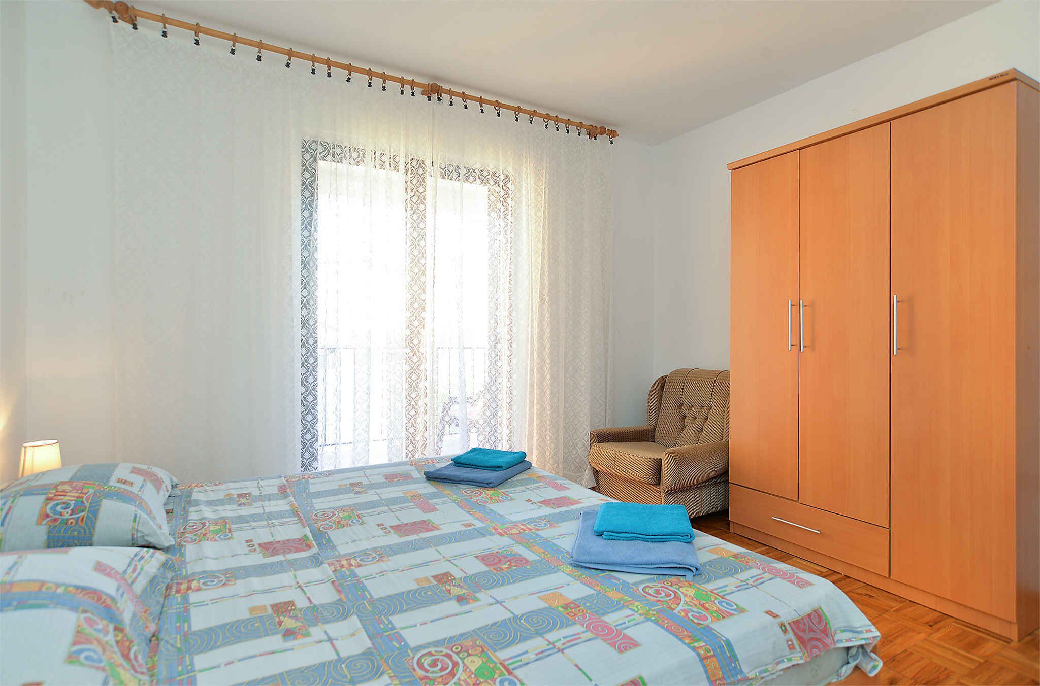 Un dormitorio con cama, una silla y un armario.